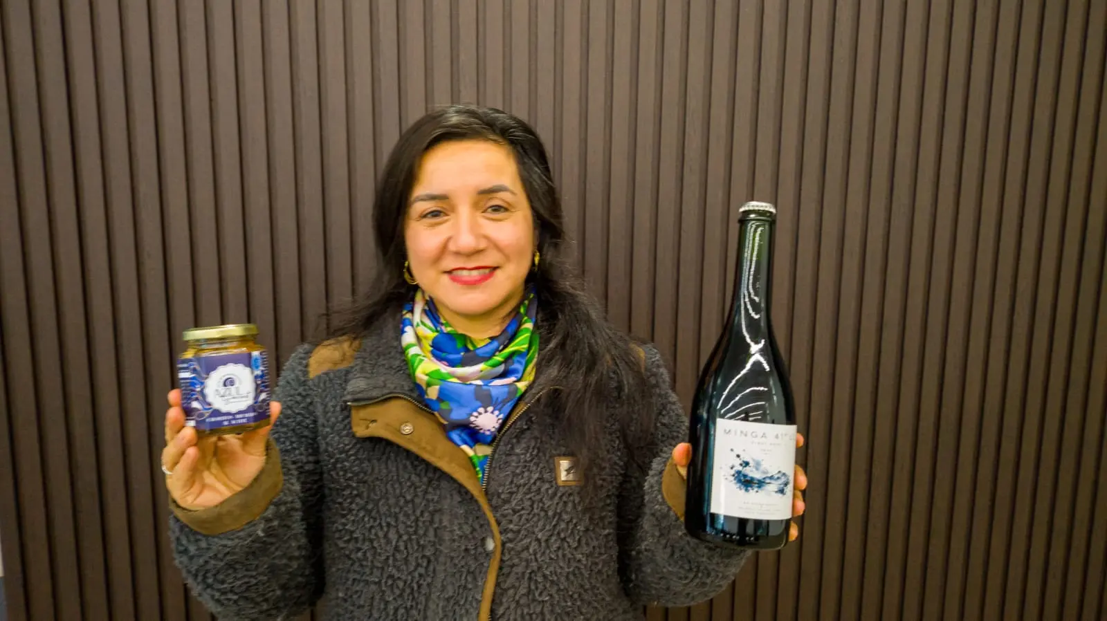 Productora sosteniendo un frasco Azul Gourmet y una botella de vino Minga