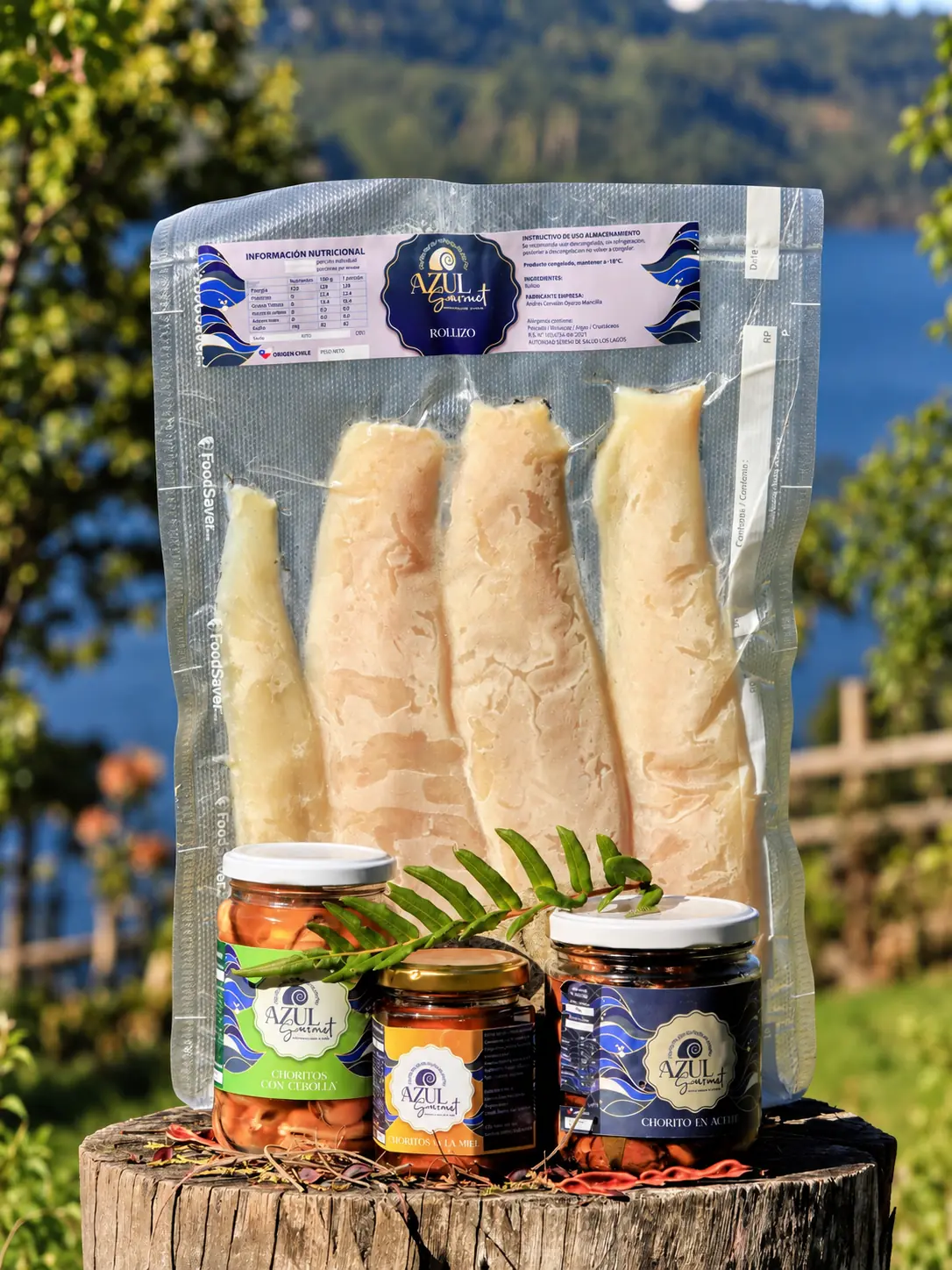 Paquete de rollizo ahumado junto a tres frascos de conserva Azul Gourmet sobre un tronco, con el lago al fondo