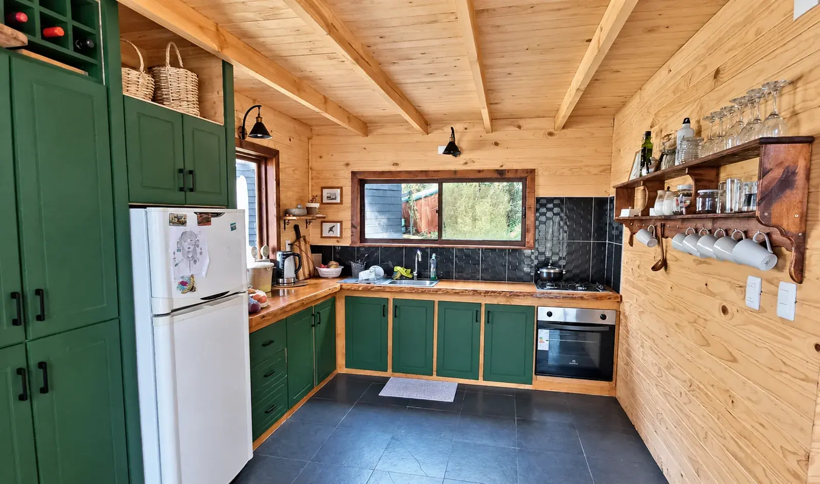 Cocina equipada de Casa Alerce con muebles verdes y horno