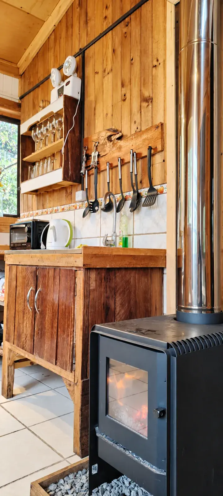 Cocina de Tejuela junto a una estufa y muebles de madera