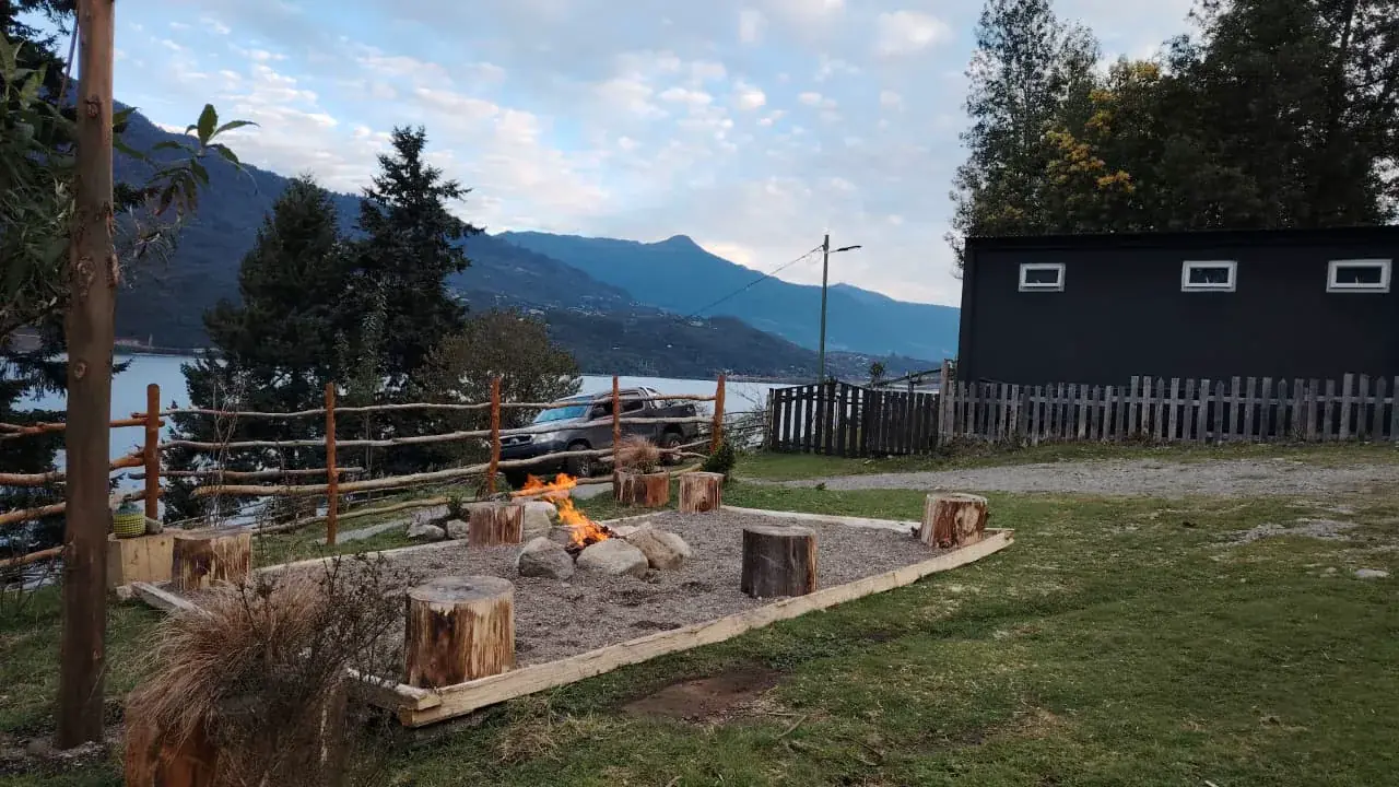Zona de fogata delimitada con asientos de troncos y vista al agua y las montañas